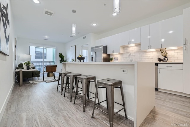 3500 S Corona St Unit 407, Englewood, CO 80113 - kitchen with stainless steel fridge, light wood-type flooring, a breakfast bar, white cabinets, and recessed lighting