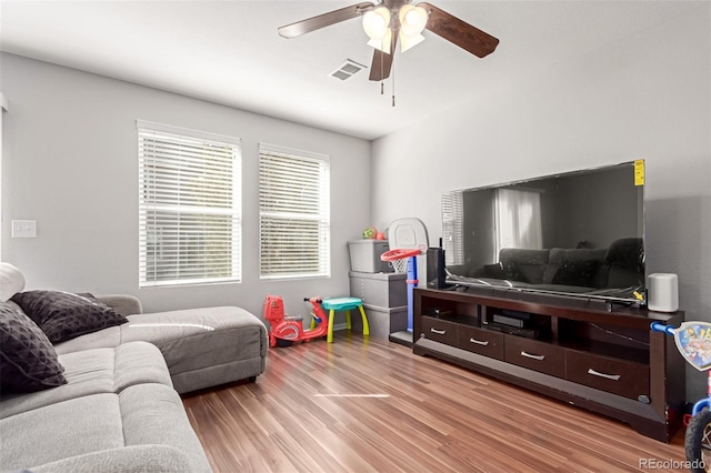 living room featuring ceiling fan, visible vents, and light wood-type flooring