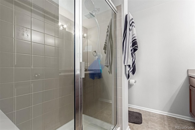 full bath featuring baseboards, a stall shower, vanity, and tile patterned flooring