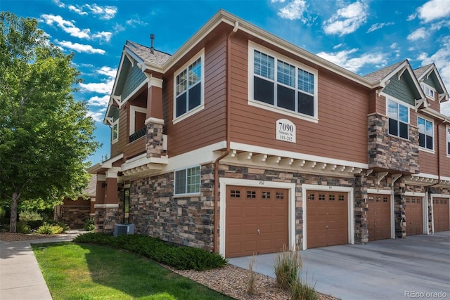 view of front of house featuring stone siding, driveway, an attached garage, and central air condition unit