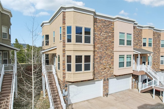 view of property featuring stairs, stucco siding, and stone siding