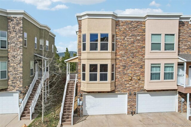 836 Vernon Dr, Central City, CO 80427 - view of side of property featuring driveway, a garage, stairs, stone siding, and stucco siding