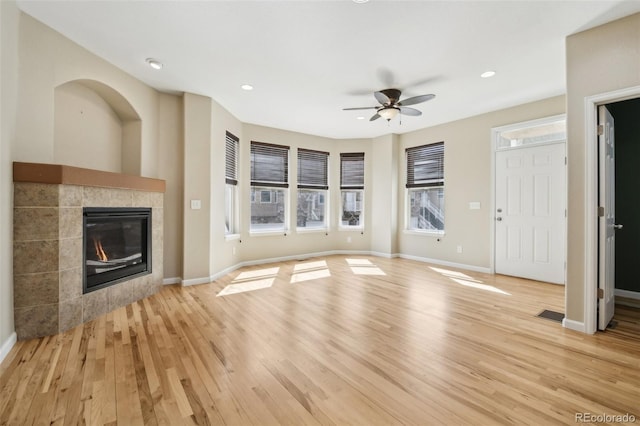unfurnished living room featuring plenty of natural light, a ceiling fan, and light wood-style flooring