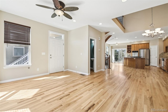 unfurnished living room with recessed lighting, baseboards, ceiling fan with notable chandelier, and light wood finished floors