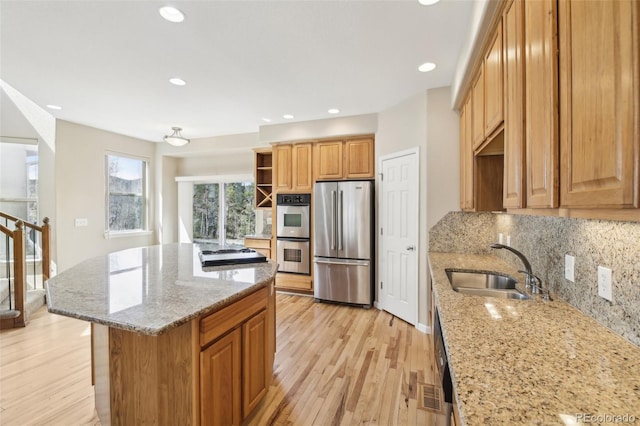 kitchen featuring light stone counters, a sink, open shelves, and appliances with stainless steel finishes