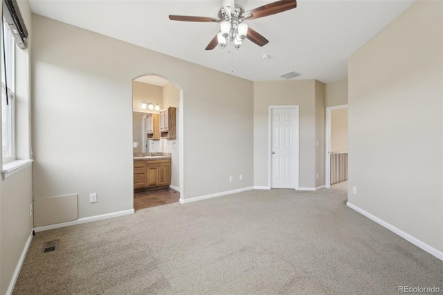 unfurnished bedroom featuring arched walkways, baseboards, carpet, and visible vents
