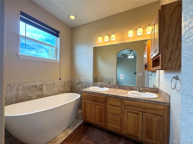 bathroom featuring double vanity, a ceiling fan, a freestanding bath, and a sink