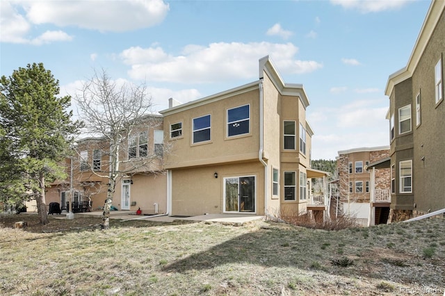 back of property with a patio and stucco siding