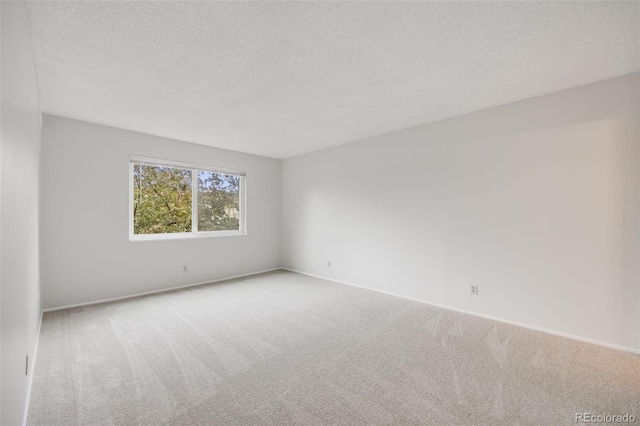 carpeted empty room with a textured ceiling and baseboards