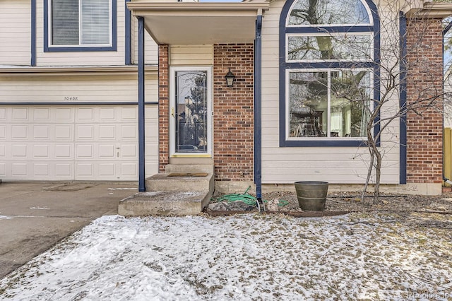 snow covered property entrance featuring a garage