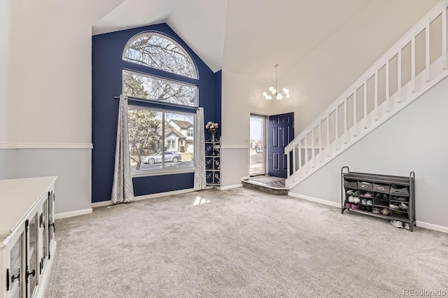 carpeted foyer with an inviting chandelier and high vaulted ceiling