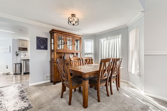 dining area featuring crown molding, light colored carpet, and a textured ceiling