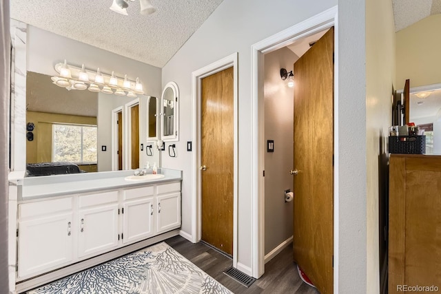 bathroom with lofted ceiling, vanity, hardwood / wood-style floors, and a textured ceiling