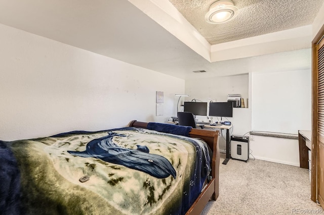 bedroom with a raised ceiling, light carpet, and a textured ceiling