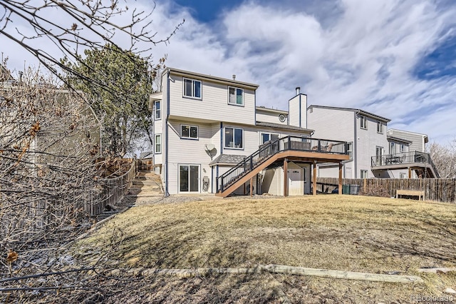 rear view of house featuring a wooden deck and a lawn