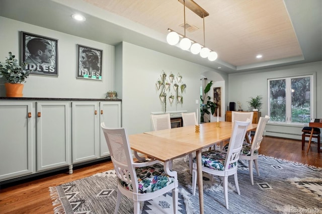 600 Vine St, Denver, CO 80206 - dining area with arched walkways, light wood-style flooring, baseboard heating, recessed lighting, and a tray ceiling