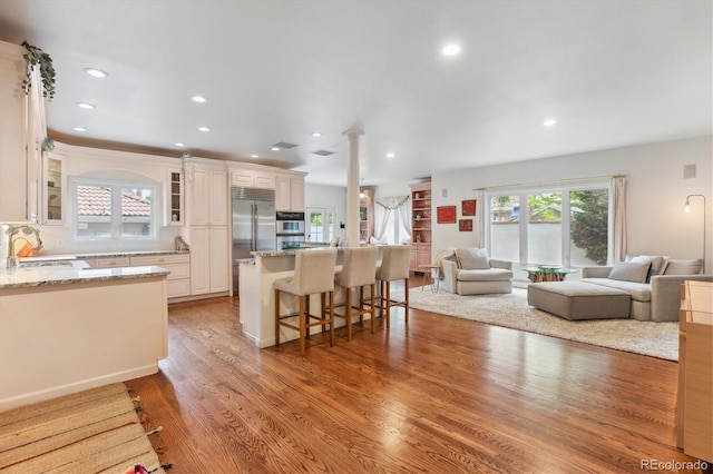 600 Vine St, Denver, CO 80206 - kitchen with stainless steel appliances, open floor plan, a kitchen bar, glass insert cabinets, and recessed lighting