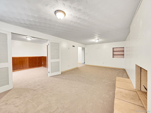 basement featuring carpet flooring, a textured ceiling, and wood walls