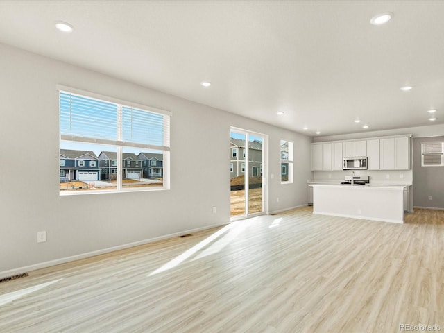 unfurnished living room featuring recessed lighting, light wood-type flooring, visible vents, and baseboards