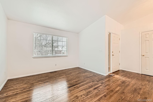 unfurnished room featuring vaulted ceiling and dark hardwood / wood-style floors