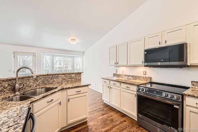 kitchen featuring sink, dark wood-type flooring, stainless steel appliances, stone countertops, and vaulted ceiling