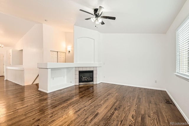 unfurnished living room with lofted ceiling, dark wood-type flooring, a tile fireplace, and ceiling fan