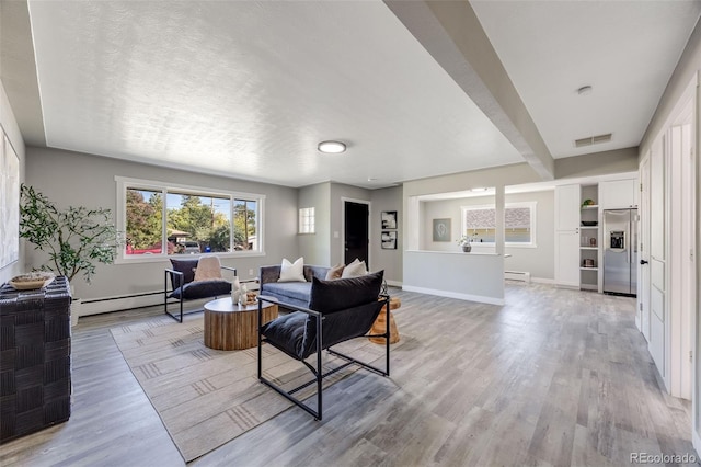 living room with beam ceiling, a baseboard radiator, light hardwood / wood-style floors, and a textured ceiling