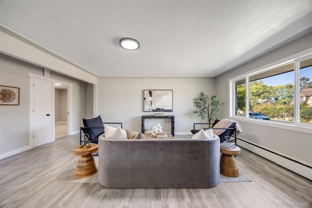 living room with a baseboard heating unit and light hardwood / wood-style flooring