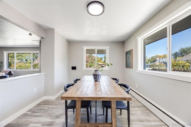 dining room featuring plenty of natural light, baseboard heating, and light hardwood / wood-style flooring