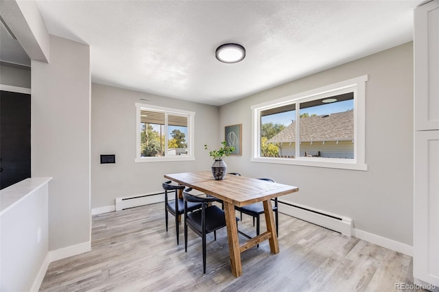 dining area featuring a baseboard radiator and light hardwood / wood-style flooring