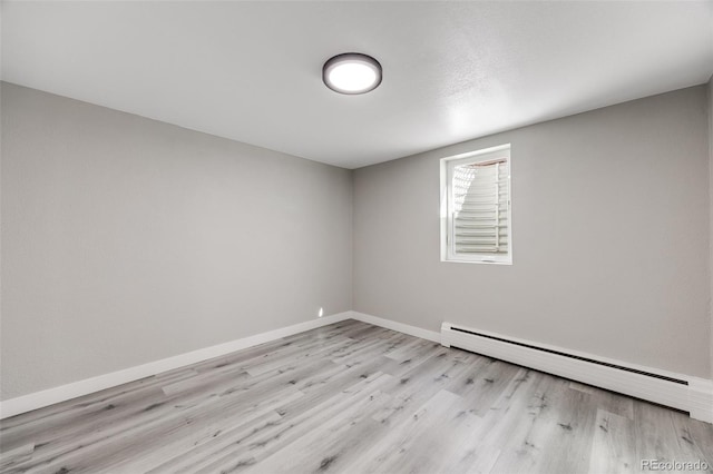 spare room featuring light hardwood / wood-style floors and a baseboard heating unit