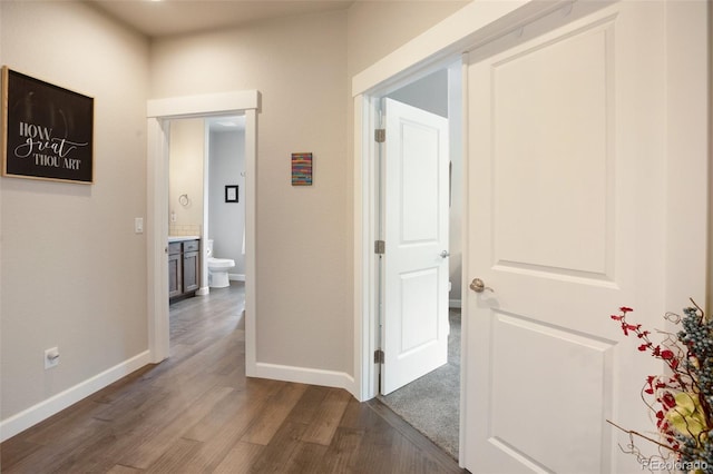 corridor featuring dark wood finished floors and baseboards