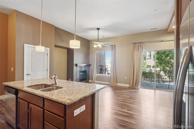 kitchen featuring stainless steel dishwasher, ceiling fan, sink, light stone counters, and light hardwood / wood-style floors