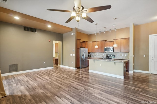 kitchen with stainless steel appliances, a center island with sink, a breakfast bar area, and hardwood / wood-style flooring