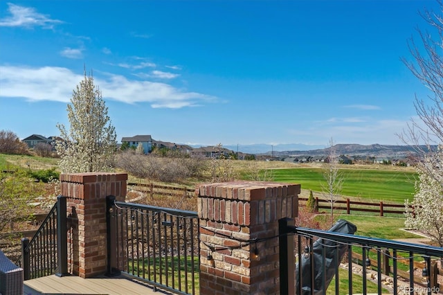 wooden deck featuring a rural view, a mountain view, and fence