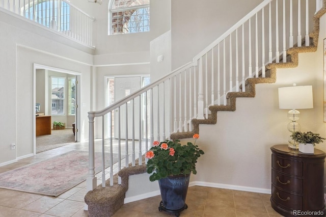 staircase featuring tile patterned floors, a towering ceiling, and baseboards