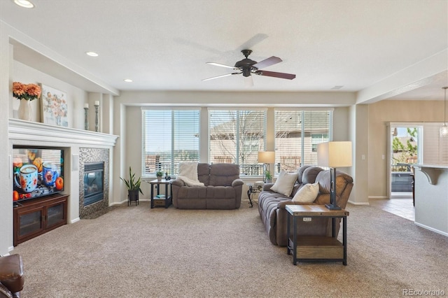 living room with a tile fireplace, ceiling fan, baseboards, and carpet floors