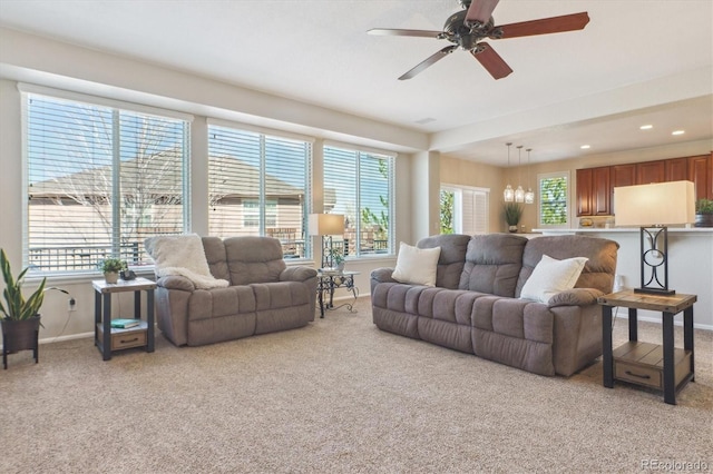 living area with light carpet, recessed lighting, baseboards, and ceiling fan with notable chandelier