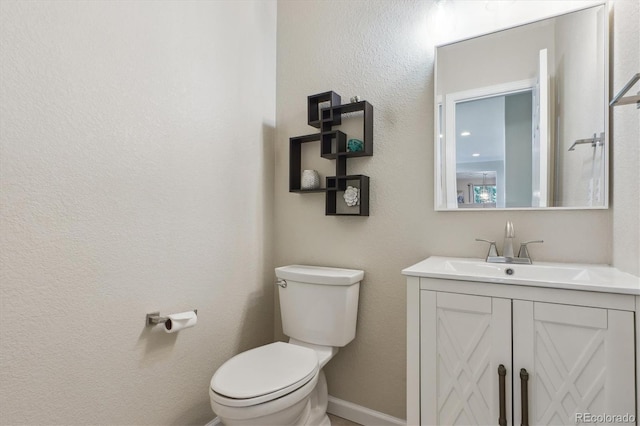 half bath with vanity, baseboards, and toilet