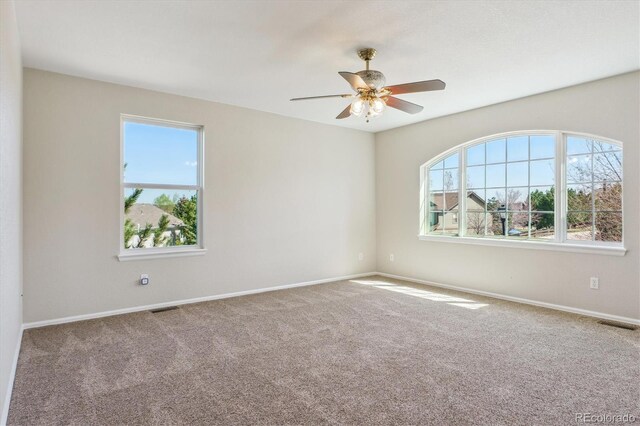 empty room with baseboards, carpet flooring, ceiling fan, and visible vents