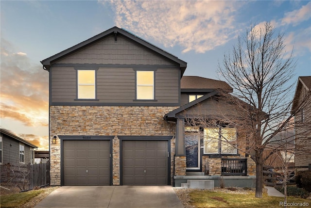 view of front of home with an attached garage, concrete driveway, stone siding, and fence