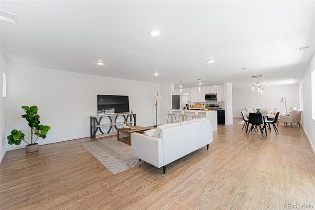 1486 S Kingston St, Aurora, CO 80012 - living room with light wood-style flooring, recessed lighting, baseboards, and a chandelier