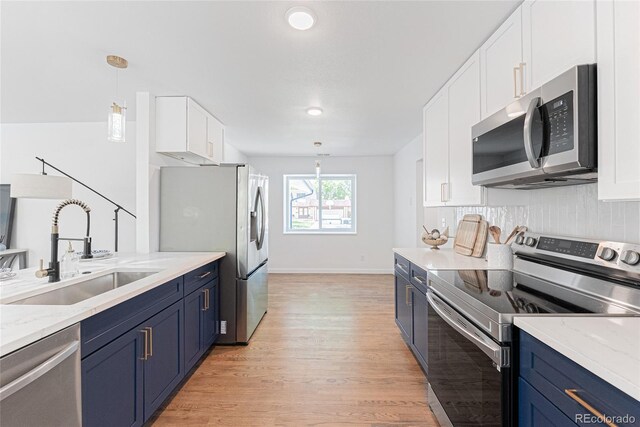 1486 S Kingston St, Aurora, CO 80012 - kitchen with stainless steel appliances, a sink, blue cabinetry, light wood finished floors, and white cabinets