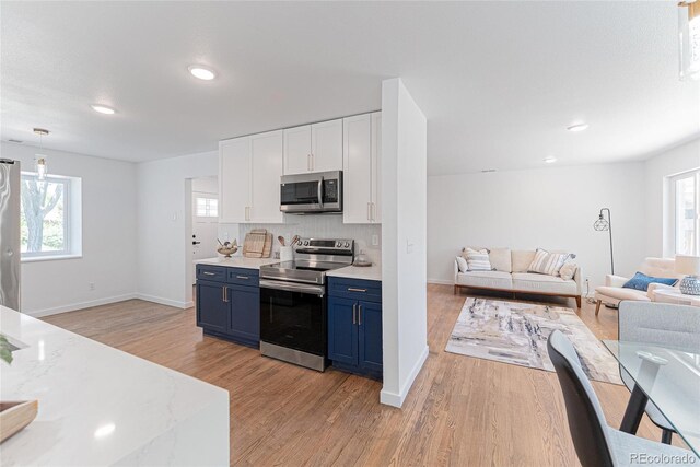 1486 S Kingston St, Aurora, CO 80012 - kitchen with appliances with stainless steel finishes, blue cabinets, plenty of natural light, open floor plan, and recessed lighting
