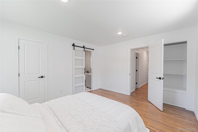 1486 S Kingston St, Aurora, CO 80012 - bedroom with light wood finished floors, a barn door, baseboards, and recessed lighting