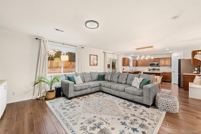 living room with visible vents, dark wood-type flooring, and baseboards