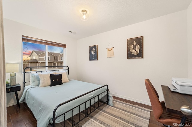 bedroom with visible vents, baseboards, and wood finished floors