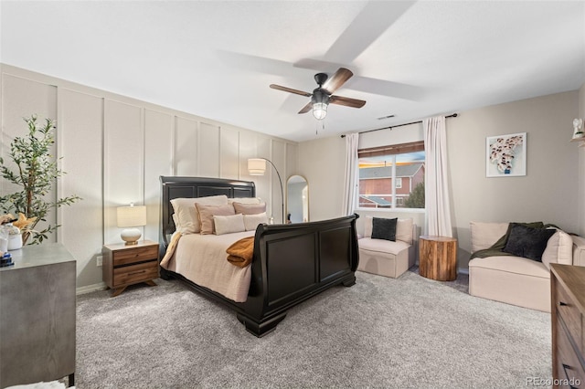 carpeted bedroom featuring a decorative wall, visible vents, and a ceiling fan