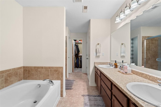 full bath featuring tile patterned floors, a sink, a shower stall, a bath, and a spacious closet