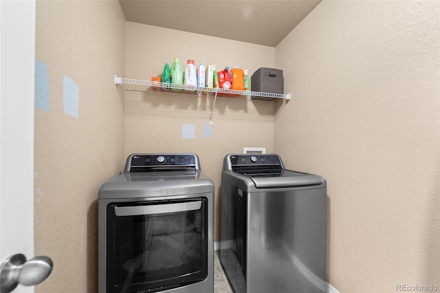 clothes washing area featuring laundry area, washing machine and dryer, and baseboards